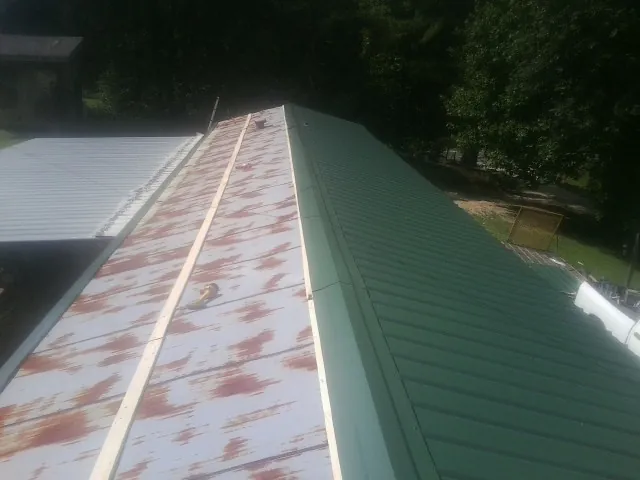 Old rusted panels beside newly installed green metal roofing — Wind Damage Roof Repair by Roofing Brothers in Mount Holly Springs