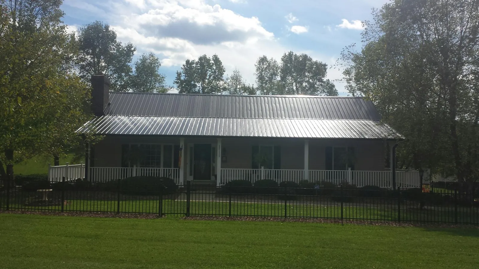 Gray metal roof on a brick ranch with a full width front porch — Gutter Guard Installation work by our crew in Mount Holly Springs