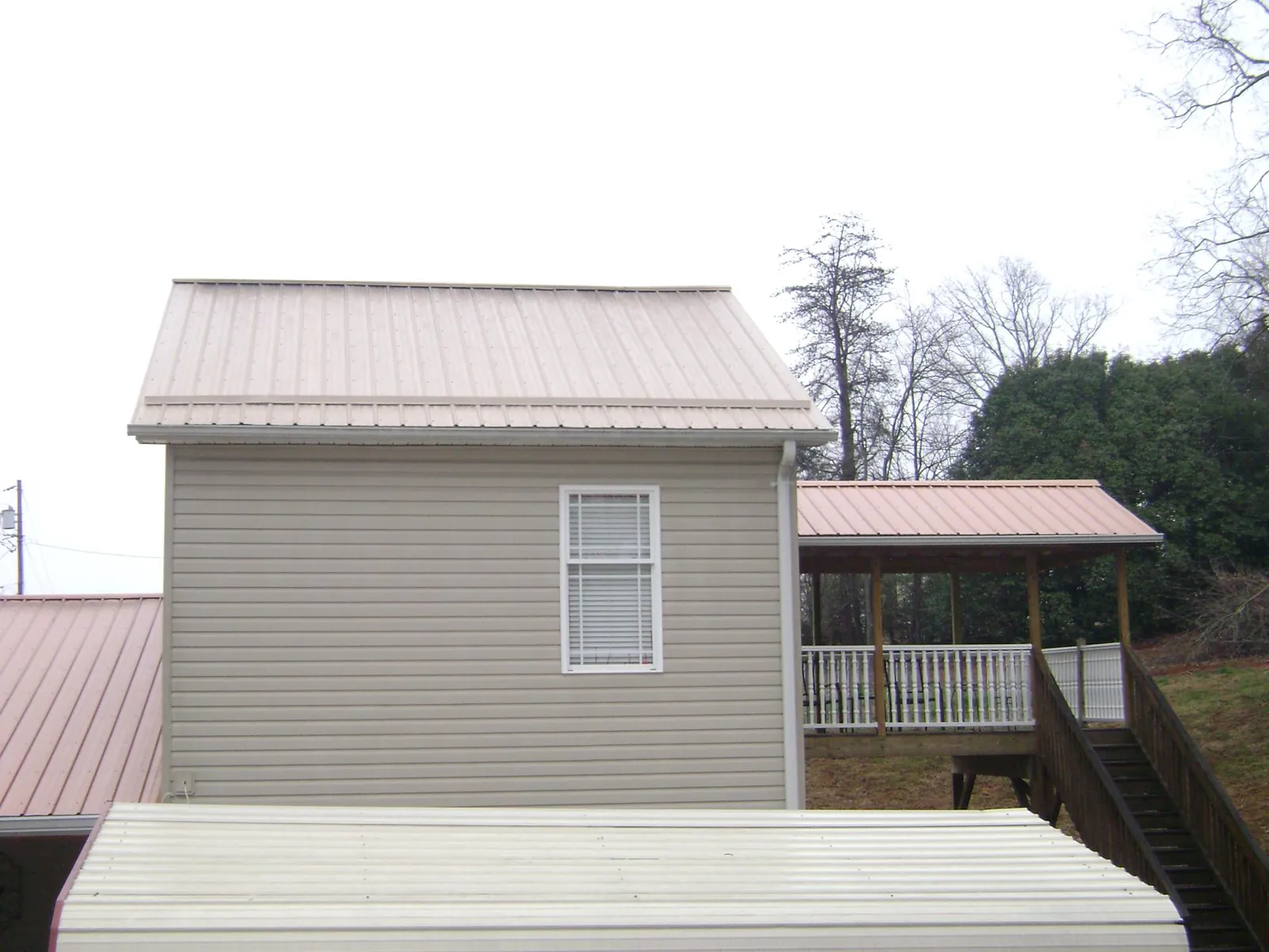 Tan metal roofs on a two story addition and attached porch, from a Roof Replacement job in Mount Holly Springs