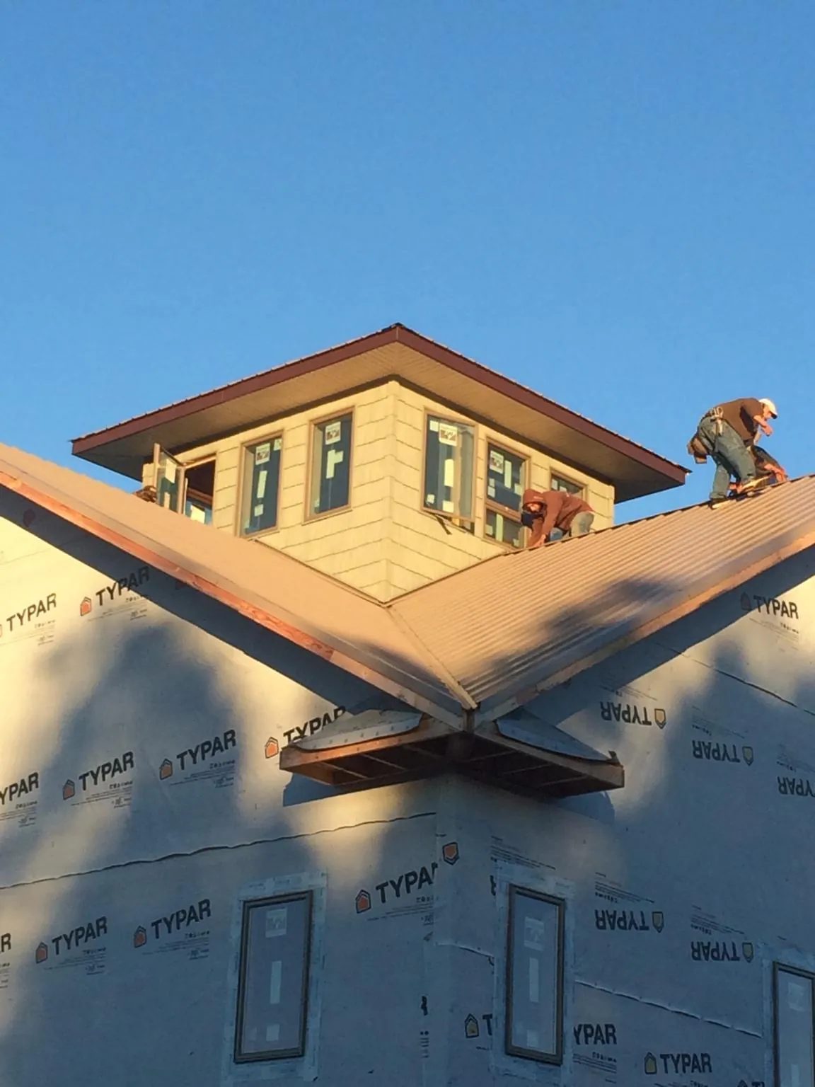 Roofers working around a rooftop cupola on a new metal roof at sunset — Roof Waterproofing in Mount Holly Springs by Roofing Brothers